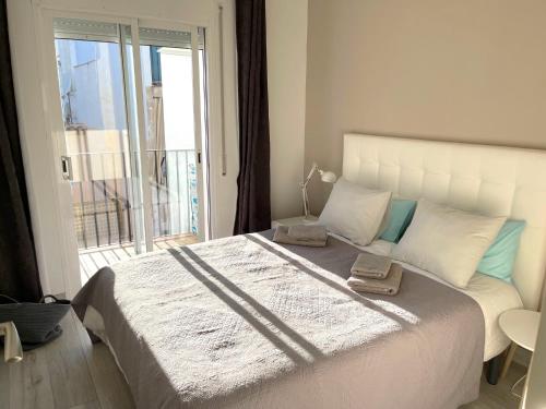 1 dormitorio con 1 cama blanca grande y ventana en Amazing 2 bedroom Apartment with big sun terrace Sitges centre beach en Sitges