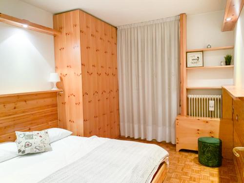 una camera con letto bianco e pareti in legno di Asiago Centro Trilocale Condominio BELLOCCHIO con Garage WiFi PetFriendly ad Asiago