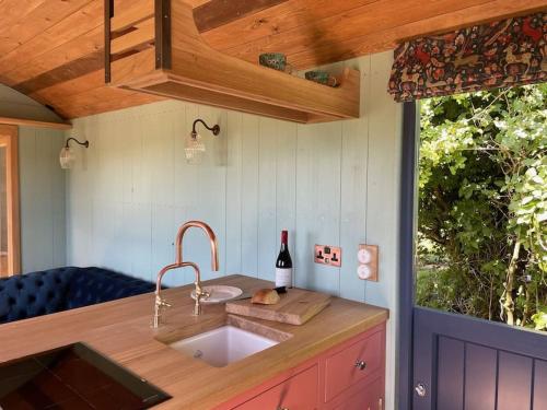 a kitchen with a sink and a bottle of wine at Novelist Shepherd's hut in Beaminster