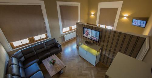 a living room with a couch and a flat screen tv at Parkhotel Plauen in Plauen