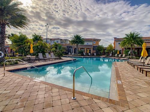 a large swimming pool with chairs and palm trees at Convenient and Close to All in Kissimmee