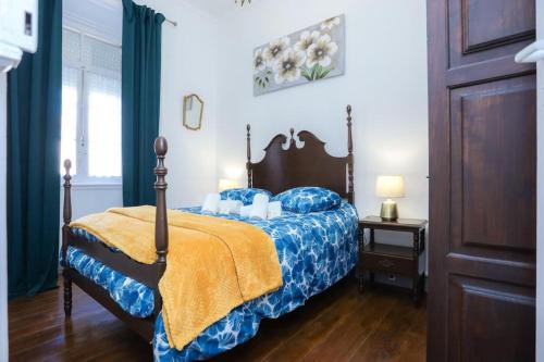 a bedroom with a bed with a blue comforter at Patio da Foz - Appartement très accueillant centre-ville in Figueira da Foz
