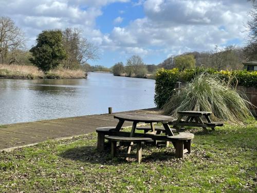 two picnic tables sitting next to a river at Holly Lodge in Norwich
