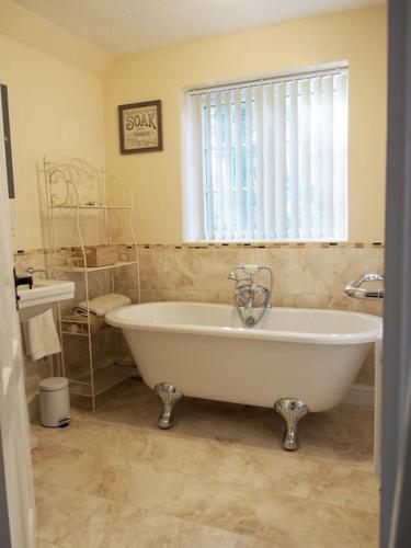 a bathroom with a large tub and a window at Station Lodge South in Nannerch
