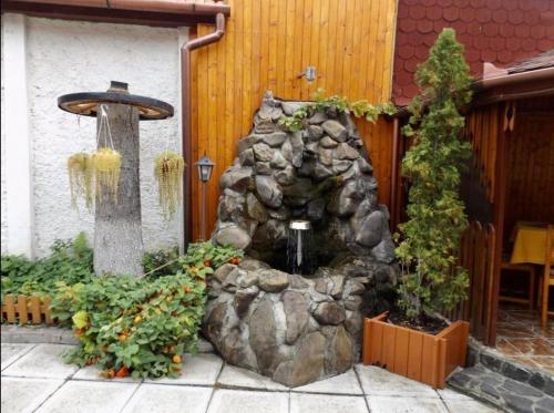 ogród z fontanną wodną przed budynkiem w obiekcie Tulipán Panzió w mieście Sfântu Gheorghe