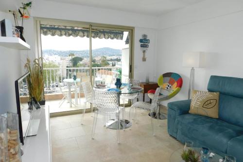 a living room with a blue couch and a table and chairs at Charming T2 "Sainte Marguerite" with air conditioning sea view and parking in Antibes