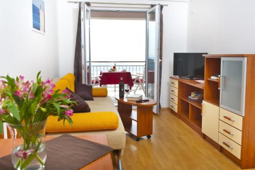 sala de estar con sofá amarillo y TV en Apartments Superb View, en Dubrovnik
