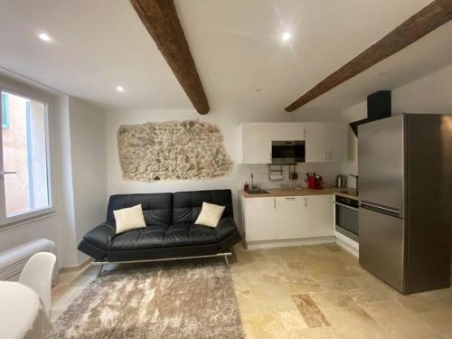un salon avec un canapé noir et une cuisine dans l'établissement Charmant deux pièces dans le vieil Antibes Safranier, à Antibes