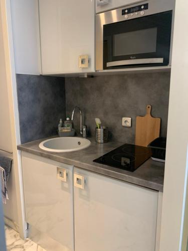 une cuisine avec un évier et un micro-ondes dans l'établissement Studio avec parking au calme 50m Croisette, à Cannes