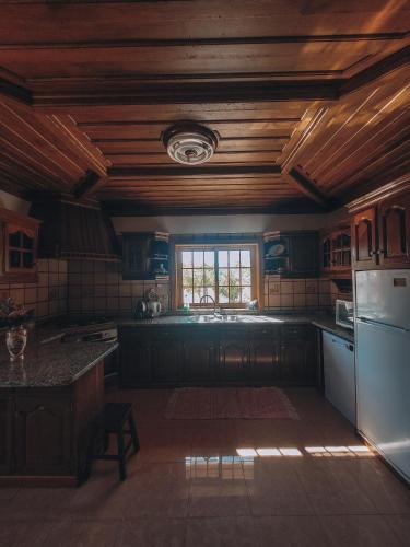 a large kitchen with wooden ceilings and a window at Casa do Xisto in Ponte de Lima