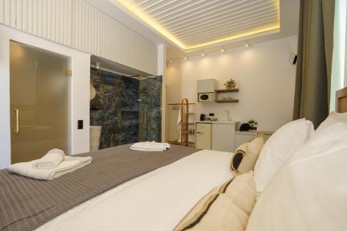 La Vie Hydra Luxury Suites في هيدرا: غرفة نوم بسرير كبير ومخدات بيضاء