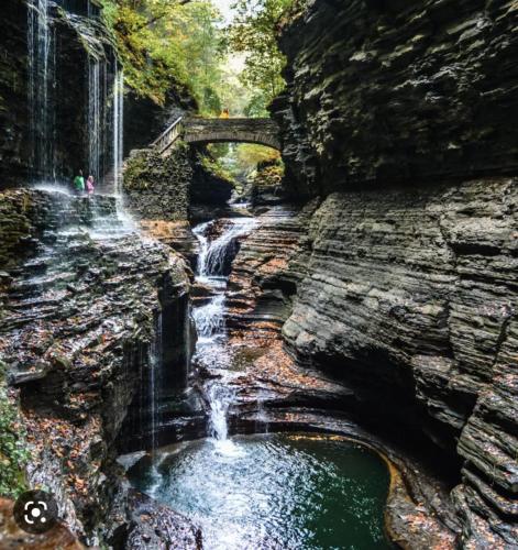 a waterfall on the side of a rock with a bridge at Walk to State Park! Eateries & Pubs! in Watkins Glen