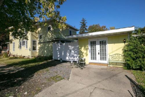 a yellow house with a white door and a driveway at Walk to Parks! Dining & Lake! Close to Hike Trails! in Watkins Glen