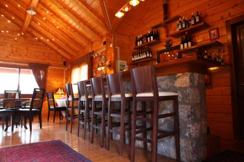 a dining room with a bar with a bunch of chairs at Pasithea Mountain Chalet in Feneos