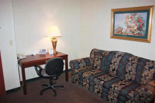 um quarto de hotel com um sofá, uma secretária e uma cadeira em ARK SUITES em Jonesboro