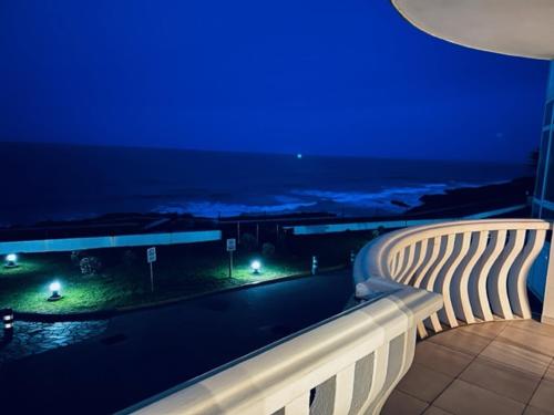 a balcony with a view of the ocean at night at Apartamento Oceano in Barreiros