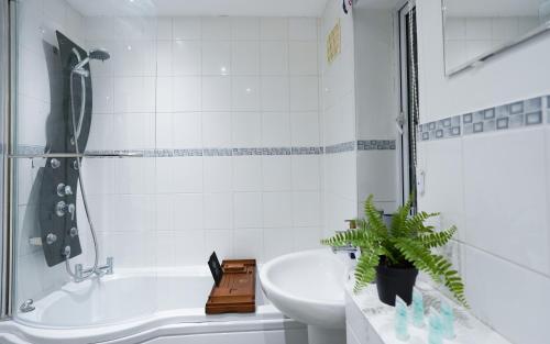 y baño con bañera, lavabo y aseo. en Entire 4BR House in Luton - Near M1 & Airport, FREE Parking, en Luton