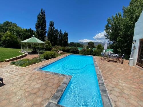 een zwembad in een achtertuin met een bakstenen patio bij The Gables-Clarens in Clarens