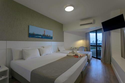 a hotel room with two beds and a television at Maceió Atlantic Suites in Maceió