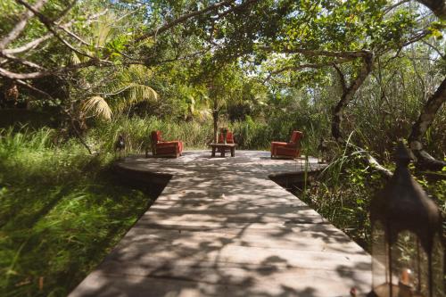 a wooden path with two chairs and a table on it at Casa Vive Bacalar in Bacalar