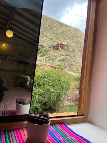 Cette chambre dispose d'une fenêtre offrant une vue sur une colline. dans l'établissement Sonqo Andino Hospedaje Medicina, à Pisac
