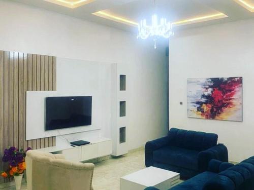 un salon avec un canapé bleu et une télévision dans l'établissement Jilles apartments -4bedroomduplex24hrlight&security, à Lekki