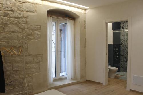 a bathroom with a stone wall and a toilet at Terrazza Campailla in Modica