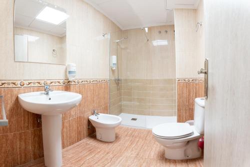 een badkamer met een wastafel, een toilet en een douche bij Hostal Viñuela in San Pedro de Mérida