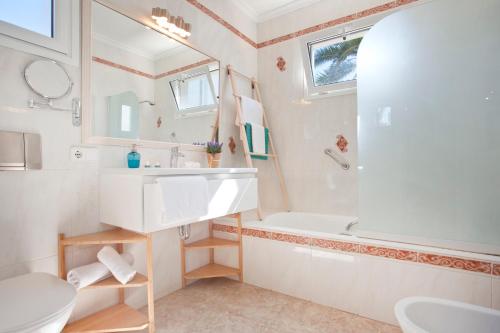 a bathroom with a sink and a tub and a toilet at Bungalow Playa dOr 4 in Cala d´Or