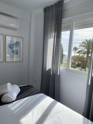 ein Schlafzimmer mit einem Bett und einem Fenster mit Palmen in der Unterkunft Apartamento 2 habitaciones frontal al mar 2 in Torre del Mar