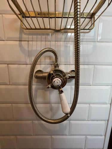 a shower with a hose attached to a wall at Cosy Narrowboat Benedict, Clarence Dock Leeds in Hunslet