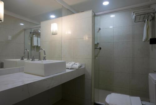 uma casa de banho branca com um lavatório e um chuveiro em Maceió Atlantic Suites em Maceió