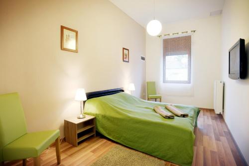 エゲルにあるCorner Apartman Egerのベッドルーム(緑のベッド1台、椅子付)
