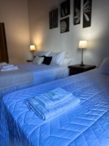 2 letti con lenzuola blu e asciugamani di El Refugio a Bella Vista