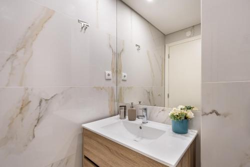 a white bathroom with a sink and a mirror at Sé Apartamentos - Niko Apartment in Braga