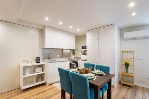 a kitchen and dining room with a table and blue chairs at Niko Studio City Center By Sé Apartamentos in Braga