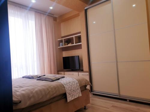 1 dormitorio con 1 cama y puerta corredera de cristal en Sky House Premium apartment in City Center, en Chişinău