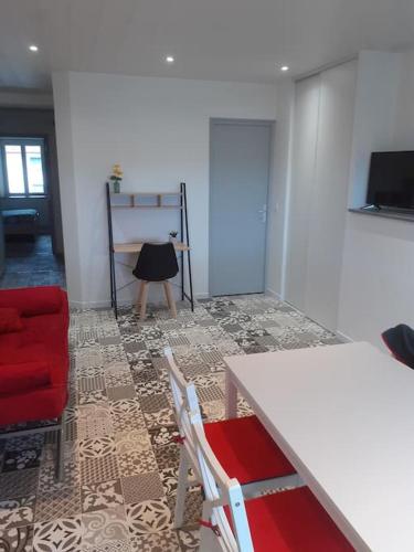 uma sala de estar com uma mesa e uma cadeira vermelha em Frasne logement entier. Gîte les Brimbelles em Frasne