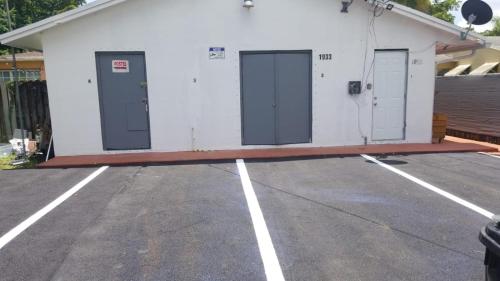 a white building with three doors in a parking lot at Funston in Hollywood
