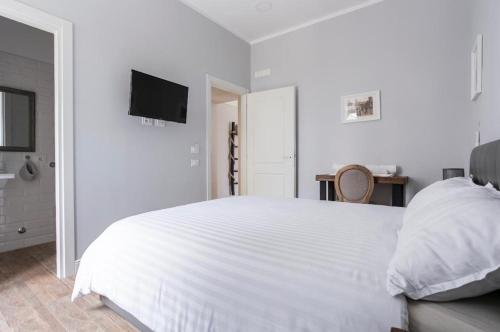 a white bedroom with a white bed and a television at Casaletto's Suites in Riano