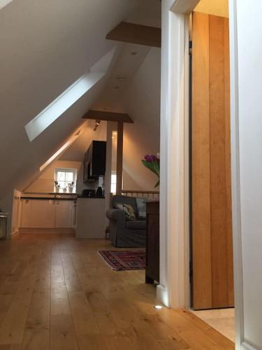 a living room with a vaulted ceiling and a kitchen at The Loft in Brockenhurst
