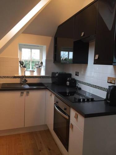 a kitchen with black counters and white cabinets at The Loft in Brockenhurst