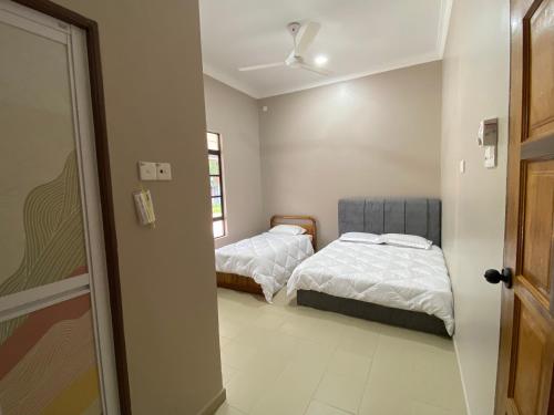a bedroom with two beds and a door open at Sasuka Guesthouse (Muslim Sahaja) in Marang