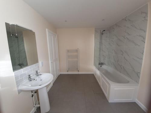 a white bathroom with a sink and a bath tub at Bandar Cottage, farm cottage, close to Narberth, Pembrokeshire in Narberth