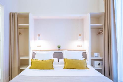 1 dormitorio con cama blanca y almohadas amarillas en Feelathome Casa Bertrand, en Barcelona