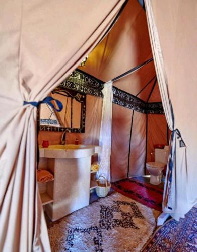 a bathroom with a tent with a sink and a toilet at Merzouga Sahara Camp in Merzouga