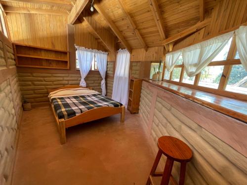 a bedroom in a log cabin with a bed and a stool at Mayan Casas in San Marcos La Laguna