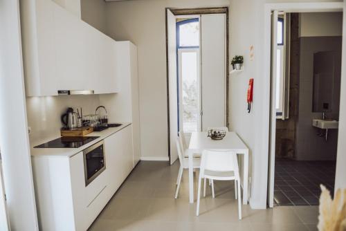 a small white kitchen with a table and chairs at Estação Ferroviária de Lourido in Celorico de Basto