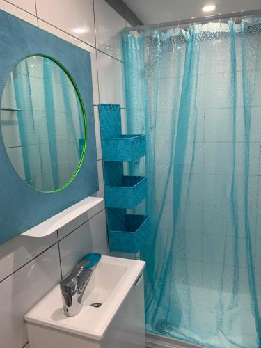 baño con lavabo y cortina de ducha azul en L appart d Ange 2 idealement situe 47m2 entre le port et le village en Gruissan