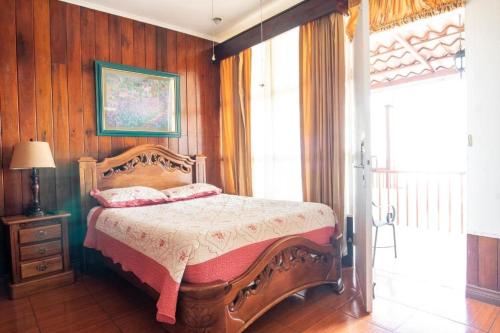 1 dormitorio con 1 cama en una habitación con paredes de madera en Sura Bed and Breakfast, en San José